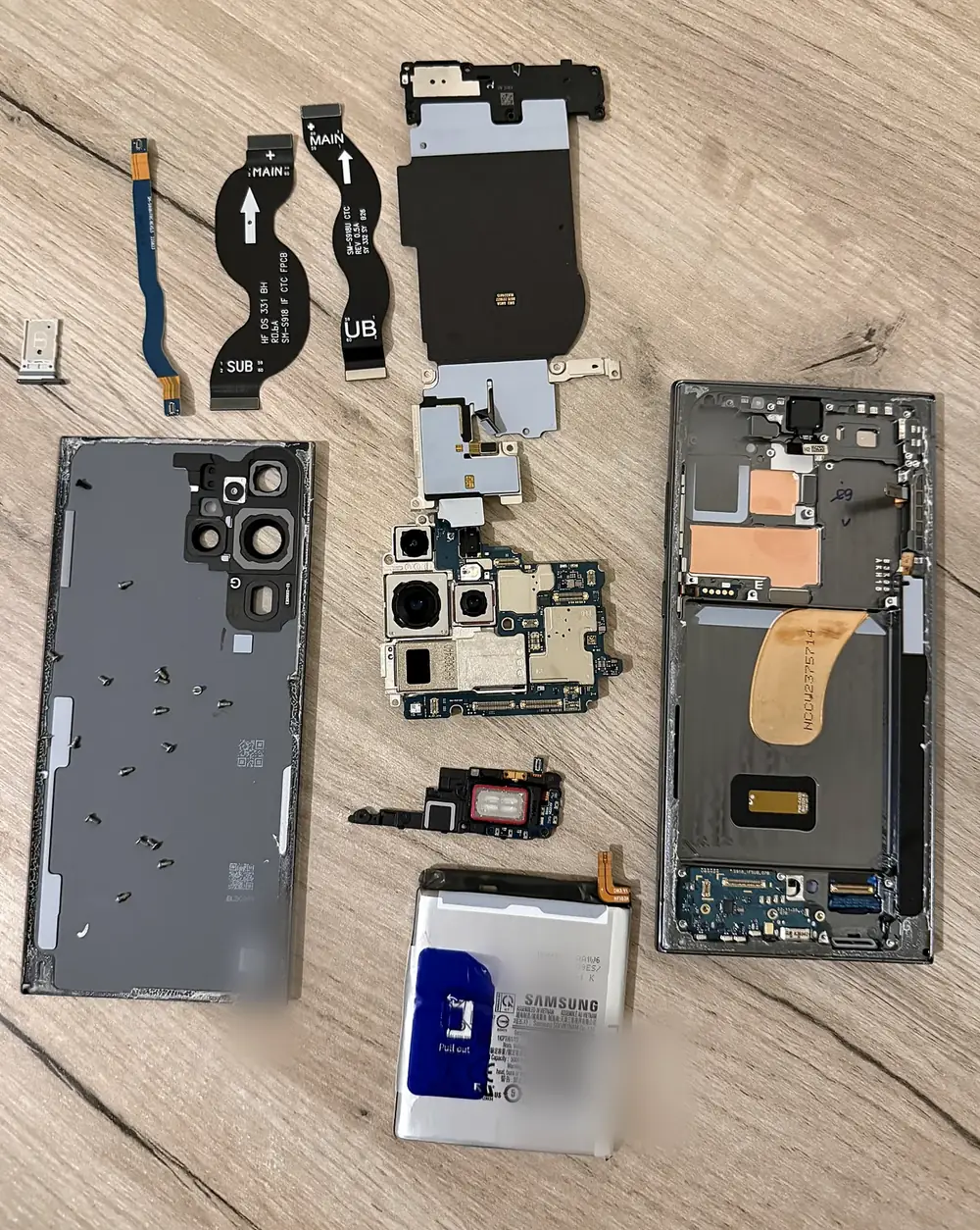 Disassembled Samsung Galaxy S23 Ultra components arranged on a workbench during repair assessment
